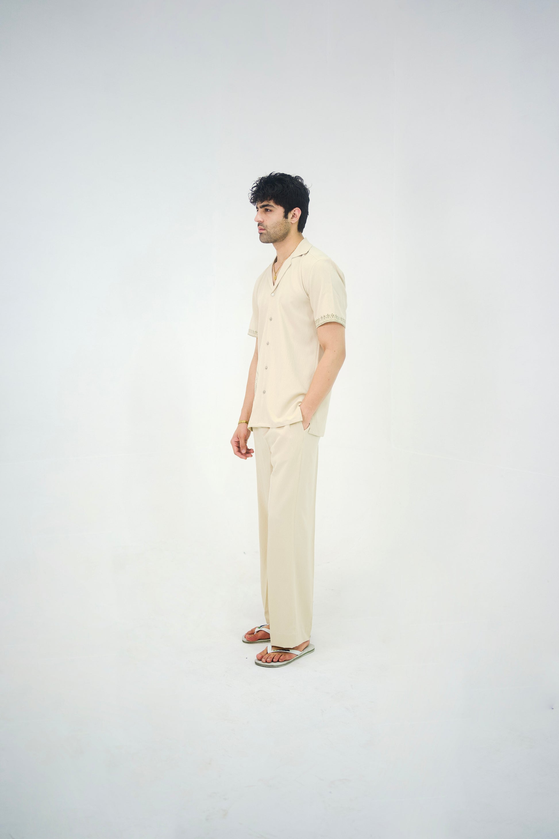Man posing in a beige cuban collar shirt and matching tailored trousers by Abbod Atelier on a white studio background.