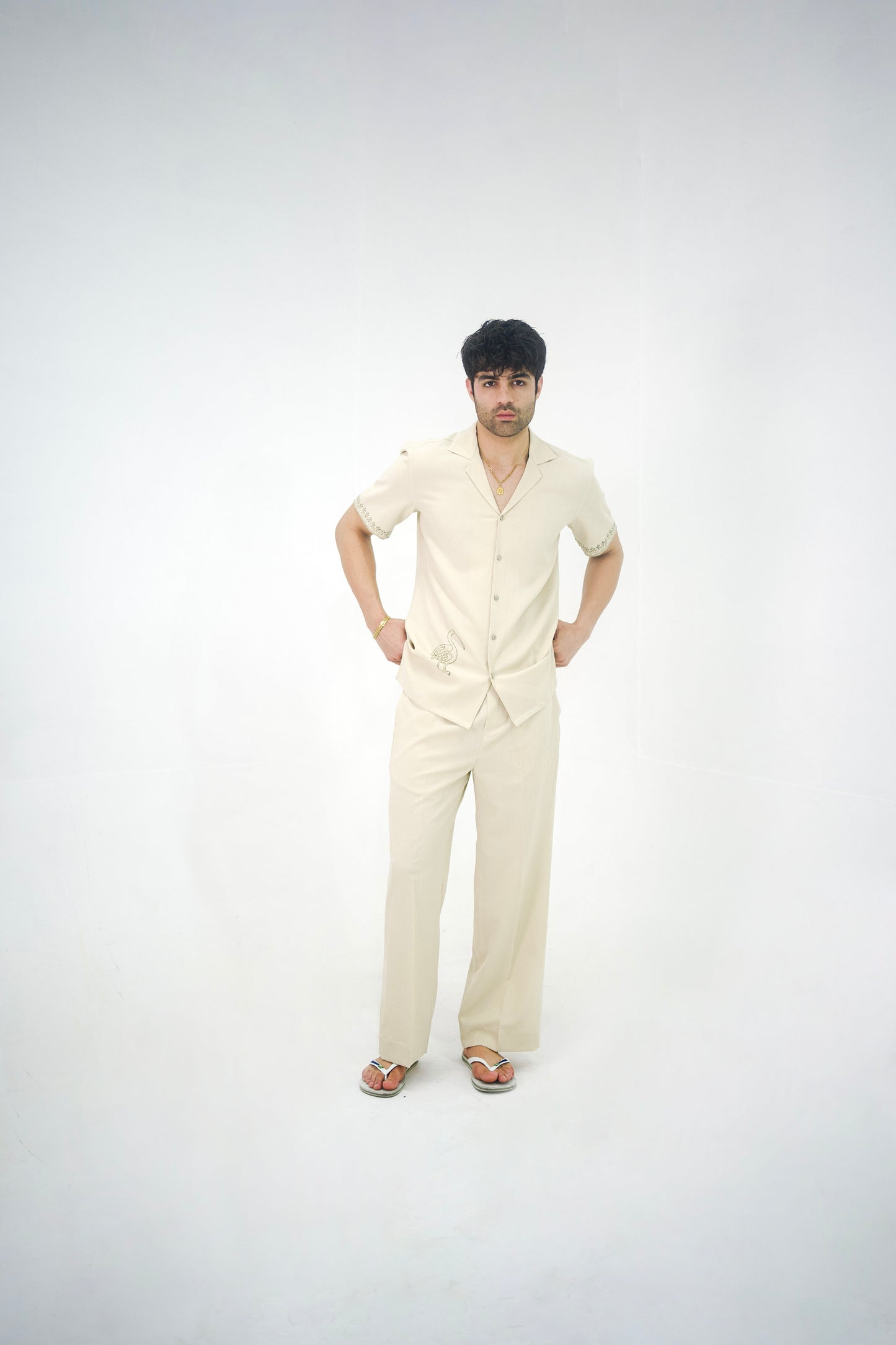 Man posing in a beige cuban collar shirt and matching tailored trousers by Abbod Atelier on a white studio background.