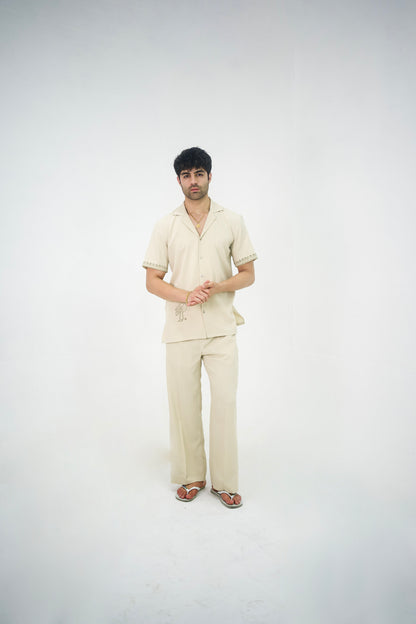 Man posing in a beige cuban collar shirt and matching tailored trousers by Abbod Atelier on a white studio background.