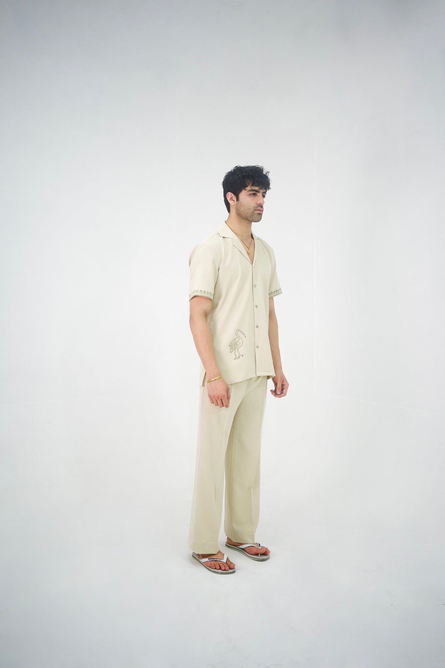 Man posing in a beige cuban collar shirt and matching tailored trousers by Abbod Atelier on a white studio background.