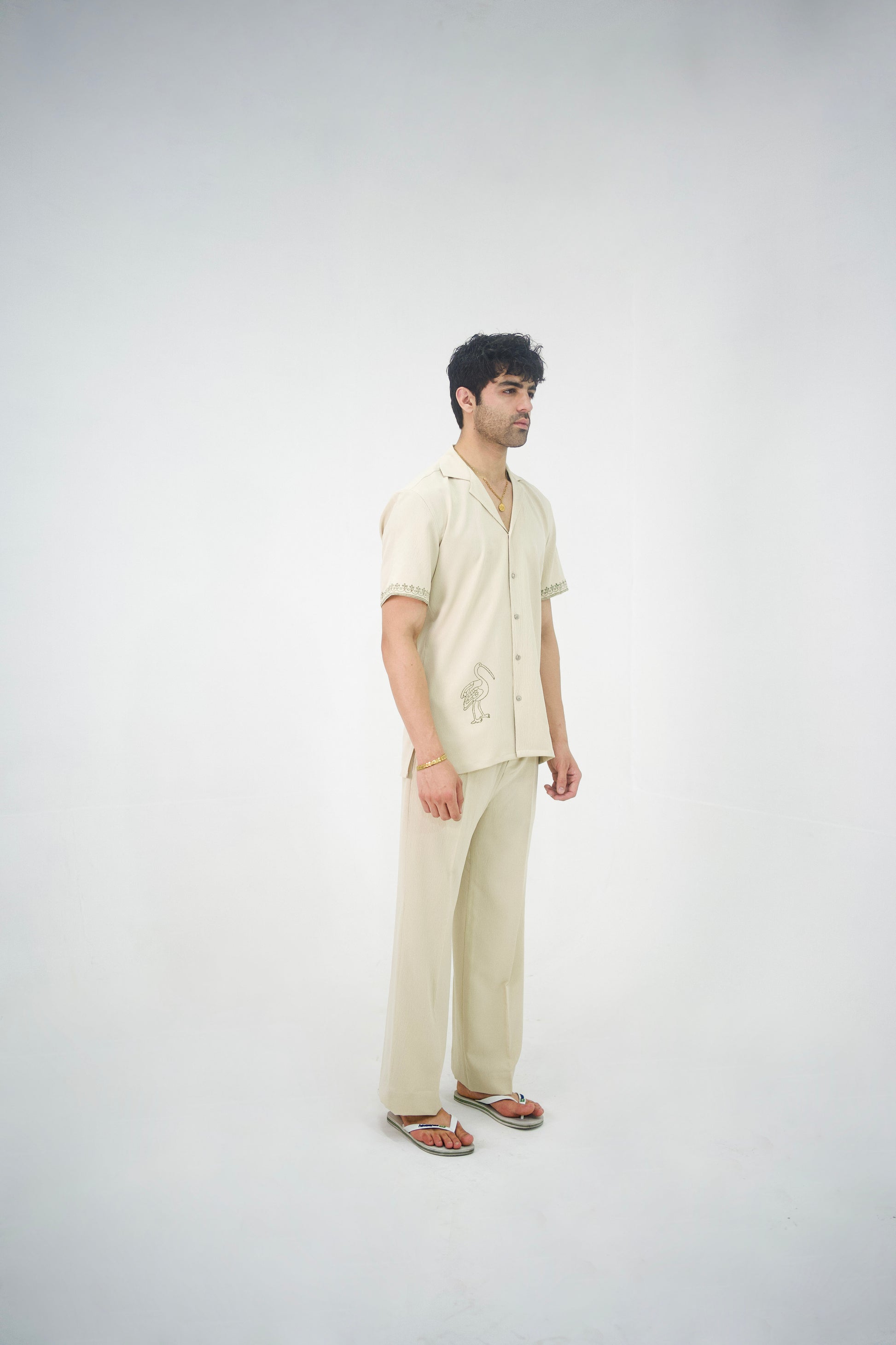 Man posing in a beige cuban collar shirt and matching tailored trousers by Abbod Atelier on a white studio background.