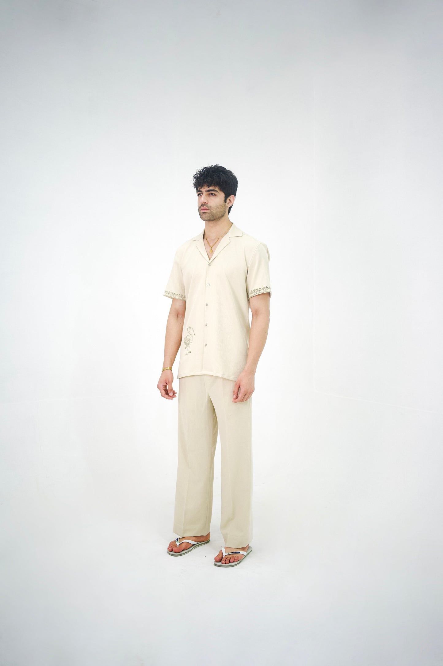 Man posing in a beige cuban collar shirt and matching tailored trousers by Abbod Atelier on a white studio background.