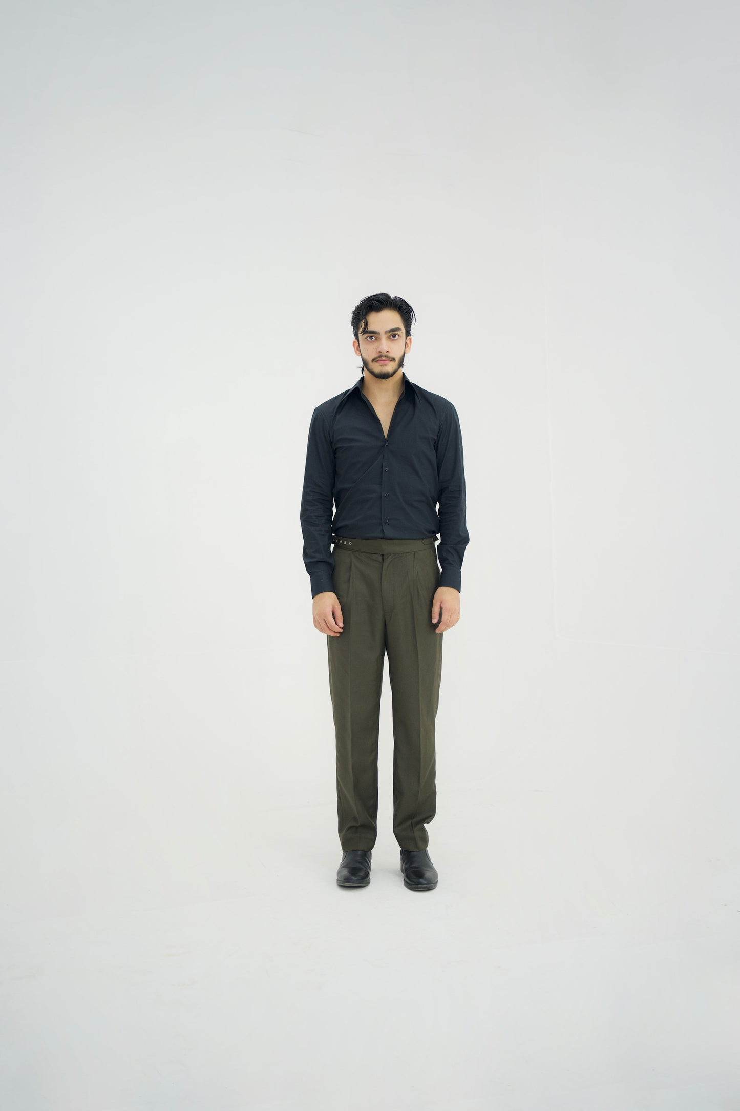 Man wearing a black shirt and green pants on a white background
