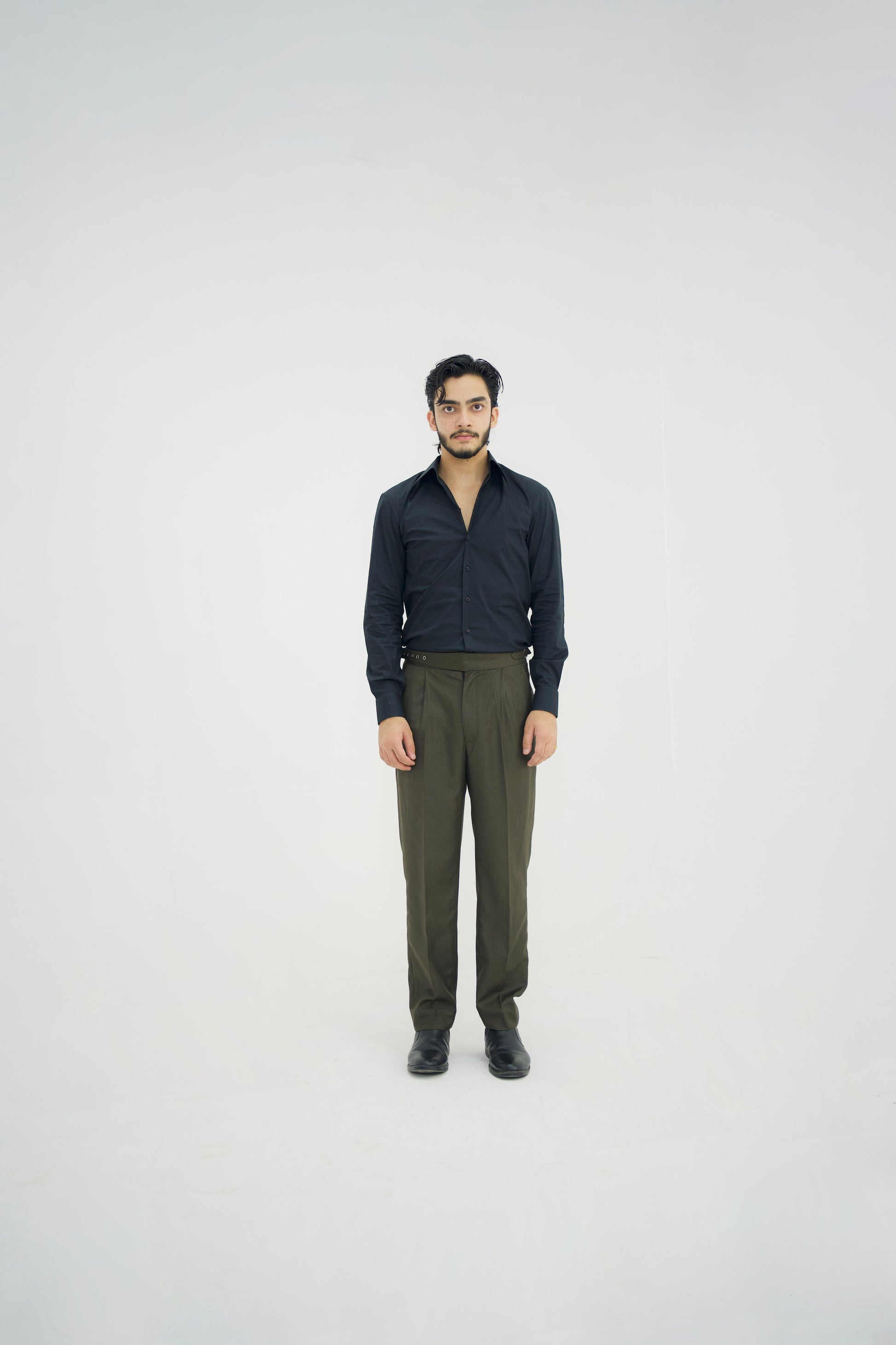 Man wearing a black shirt and green pants on a white background