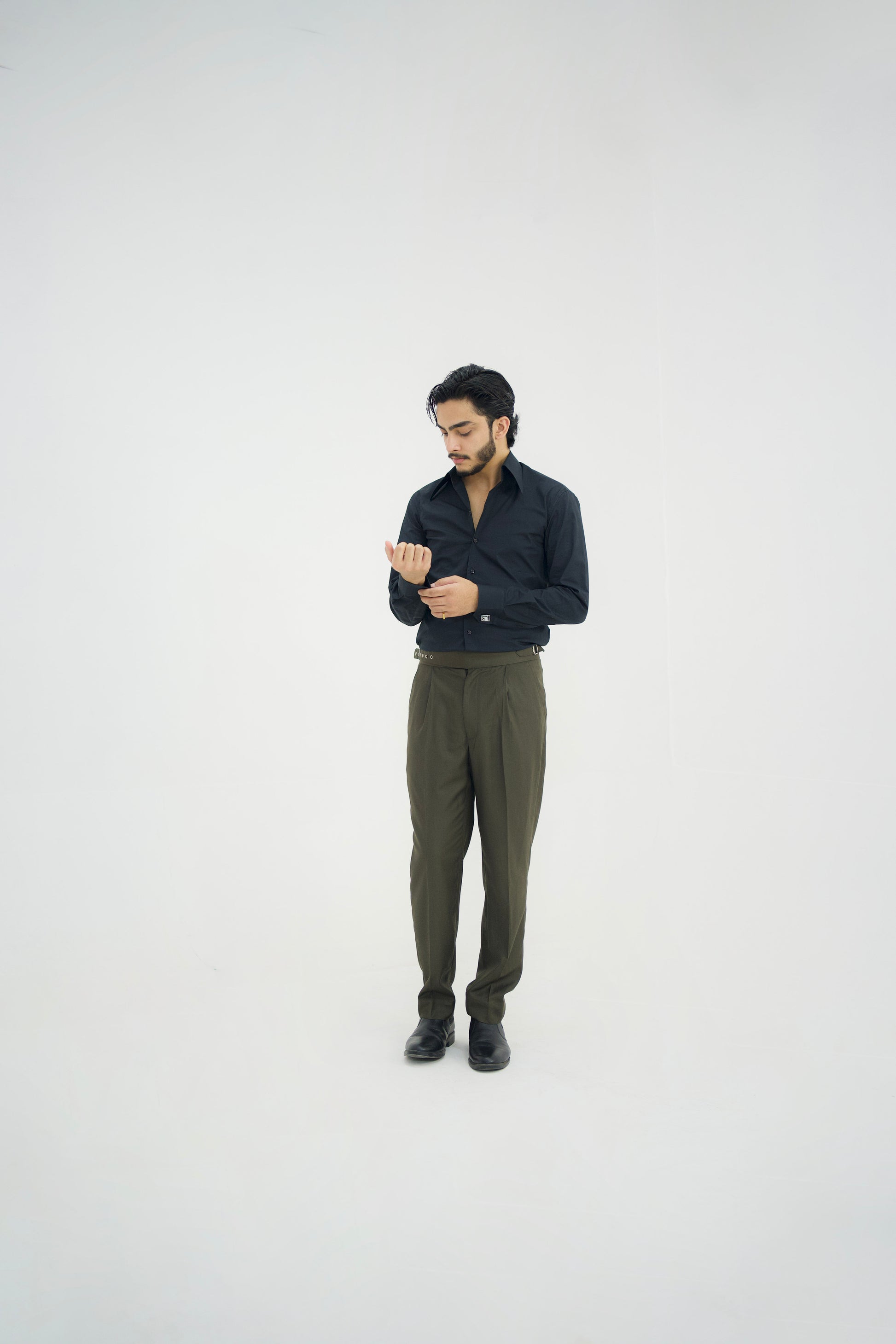 Man wearing a dark shirt and green pants on a white background