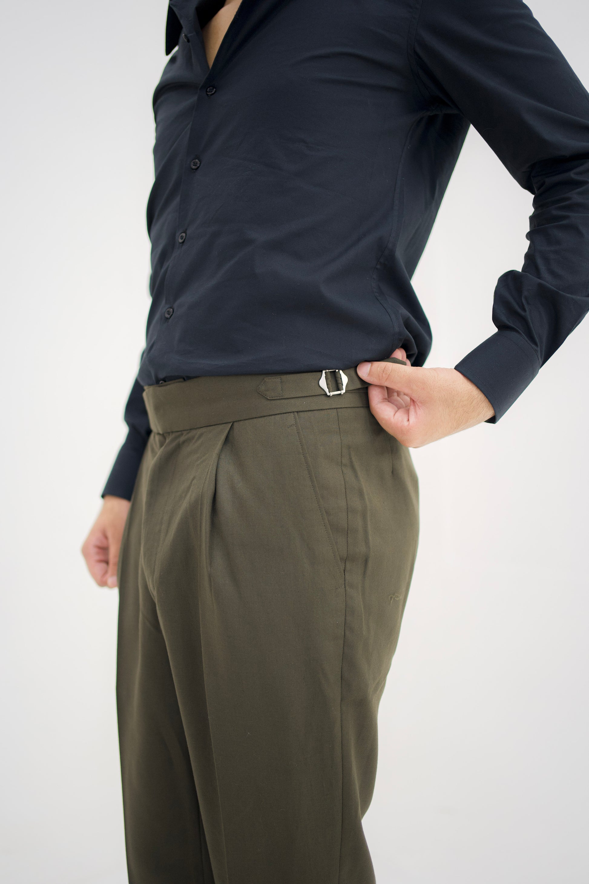 Person wearing a navy shirt and olive green pants on a white background