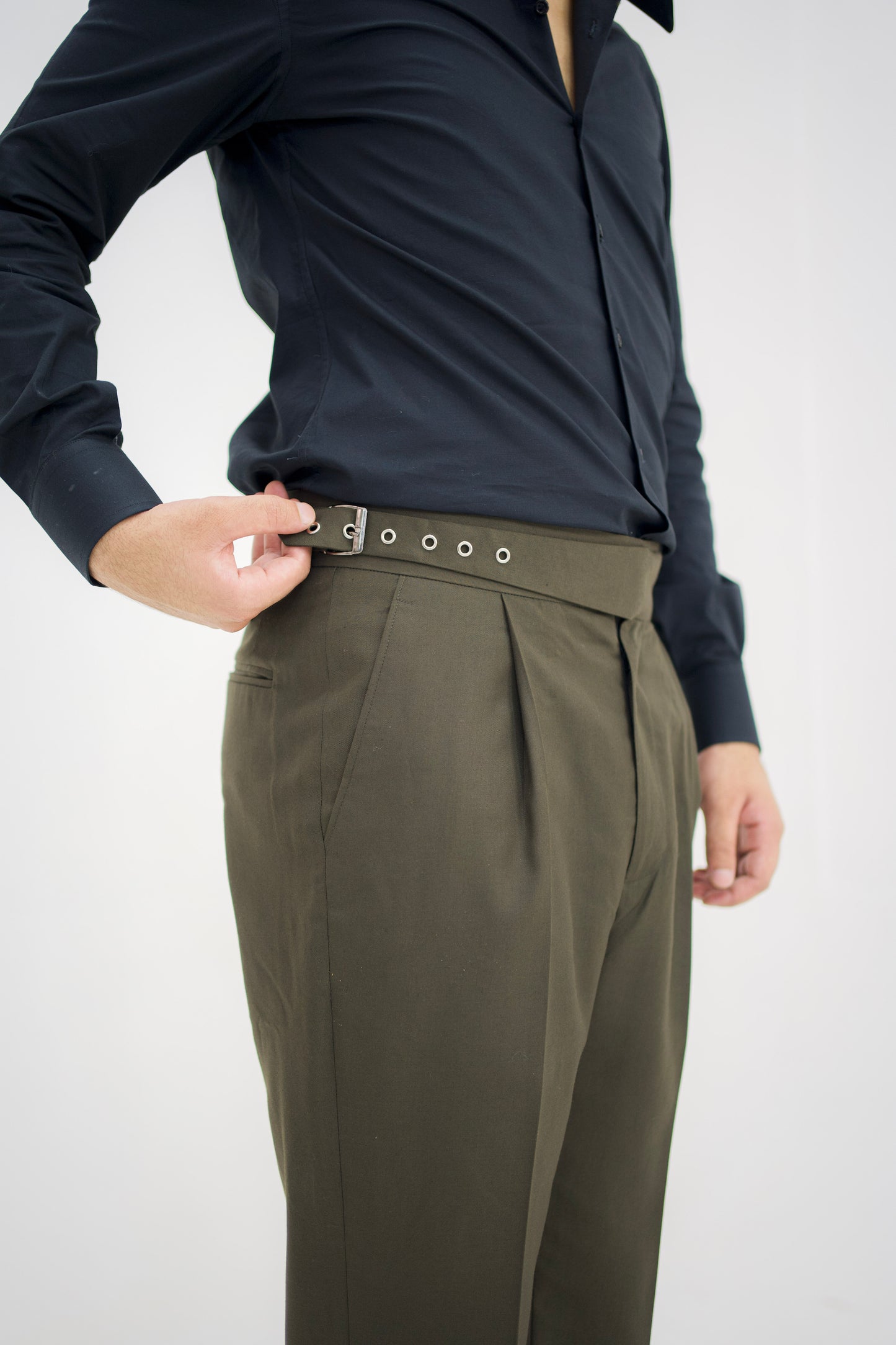 Person wearing a dark long-sleeve shirt and olive green pants on a white background